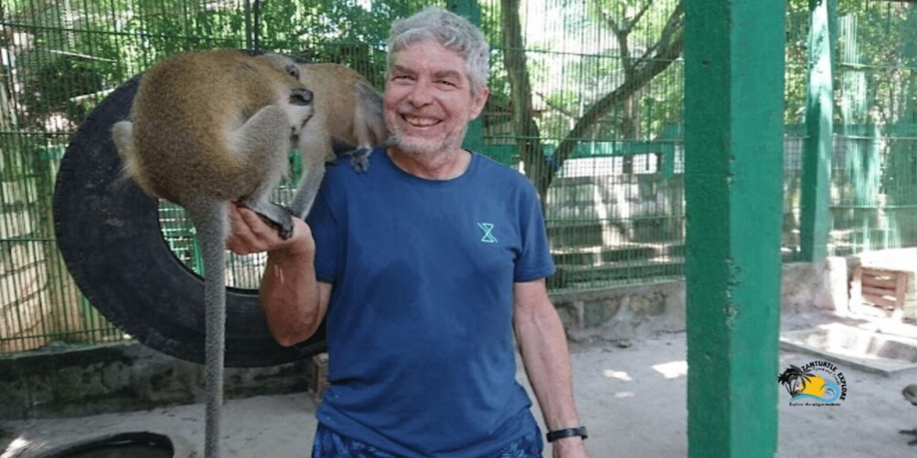 A man holding a lemur in a zoo enclosure. 5