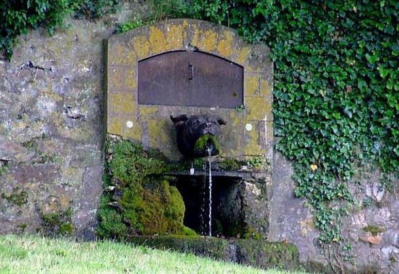 A stone wall with a metal plaque and a bear statue. 5