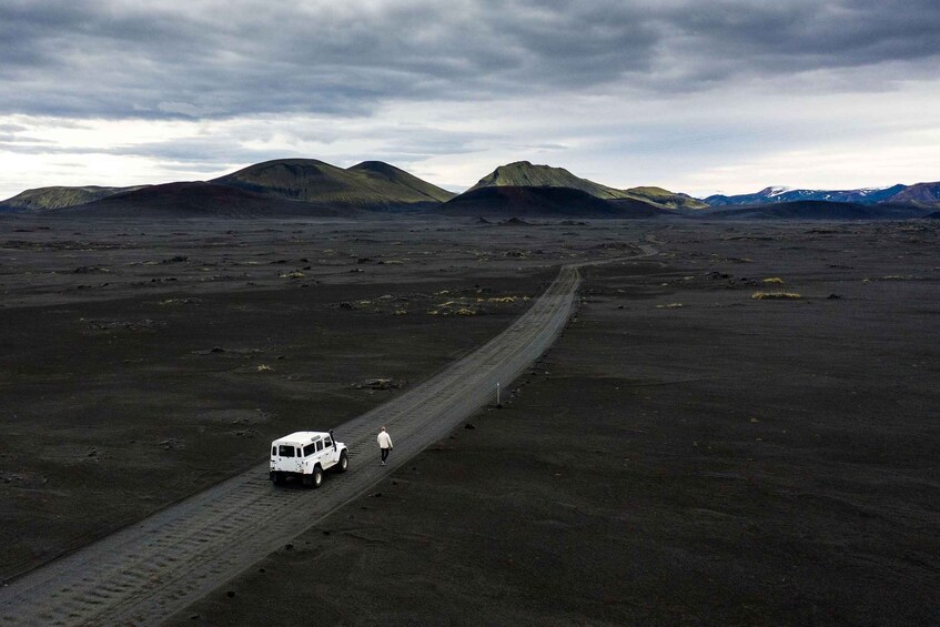 A white vehicle on a dirt road in a barren landscape with mountains in the background. 4