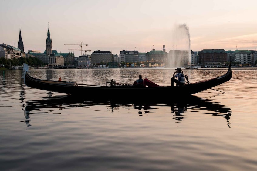 A gondola on a calm river with a city skyline in the background. 5