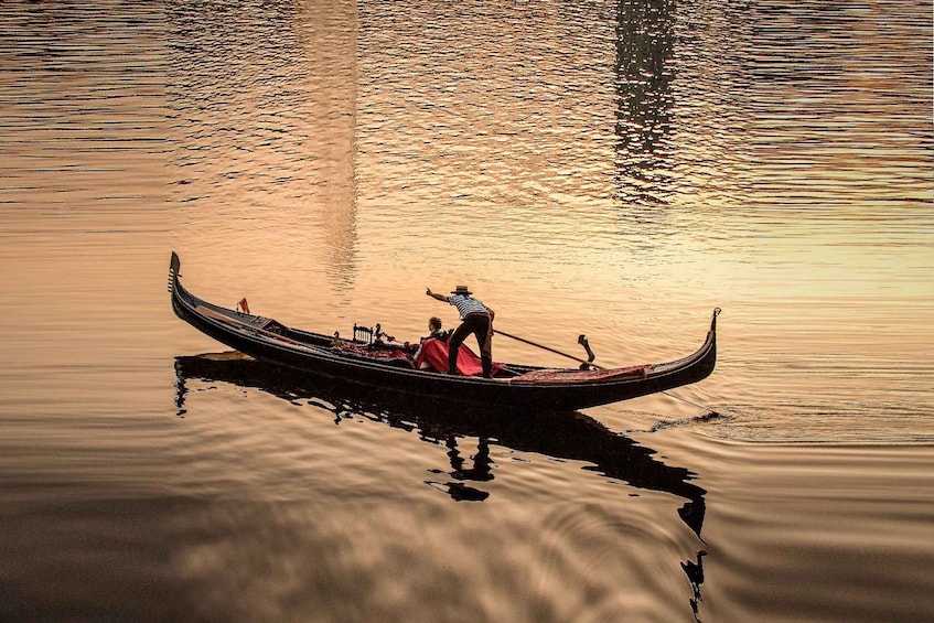 A gondola on calm water with a person rowing. 1