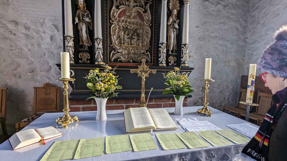 A religious altar with a crucifix, candles, flowers, and a book. 4
