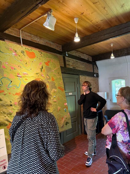 People examining a colorful map in a room with wooden beams and brick walls. 5