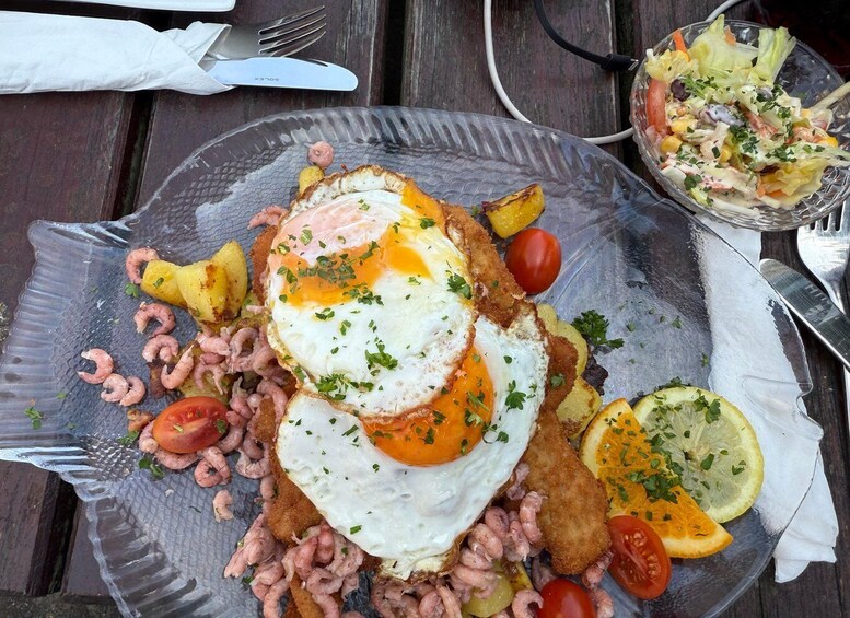 A meal with fried eggs, sausages, and vegetables on a plate. 2