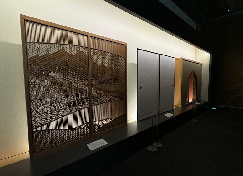 A display of traditional Japanese screens with intricate patterns and a modern sculpture. 2