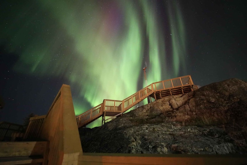 A wooden staircase leading up a rocky hill with the aurora borealis in the background. 1