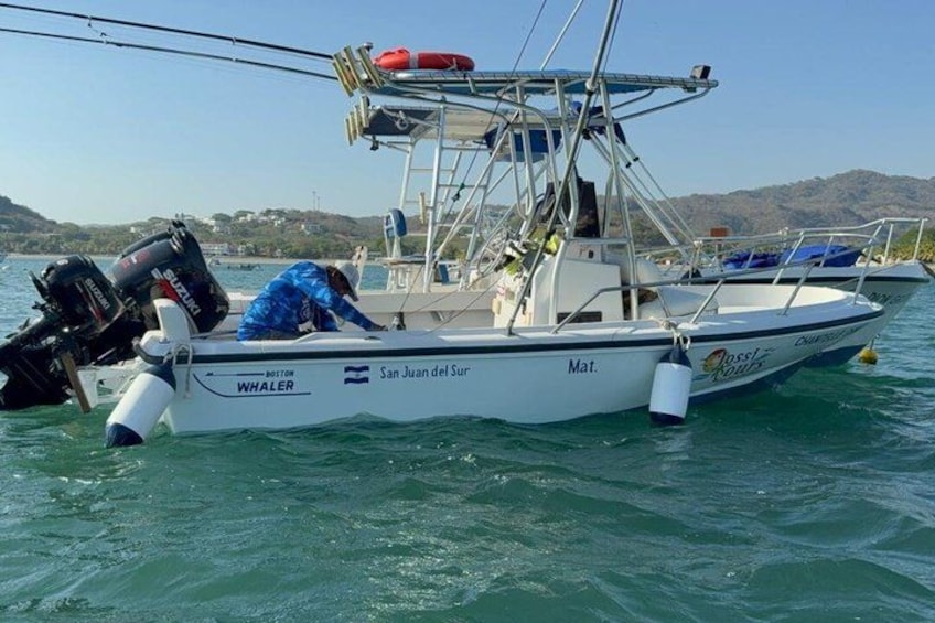 A boat named 'San Juan del Sur' with a person on deck, a motor, and a lifebuoy. 3