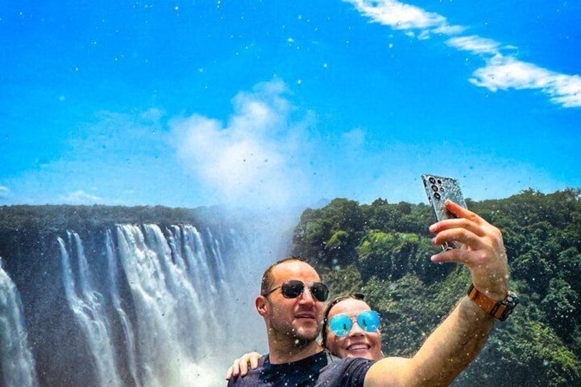 Eine Person macht ein Selfie mit einem Wasserfall im Hintergrund. 5