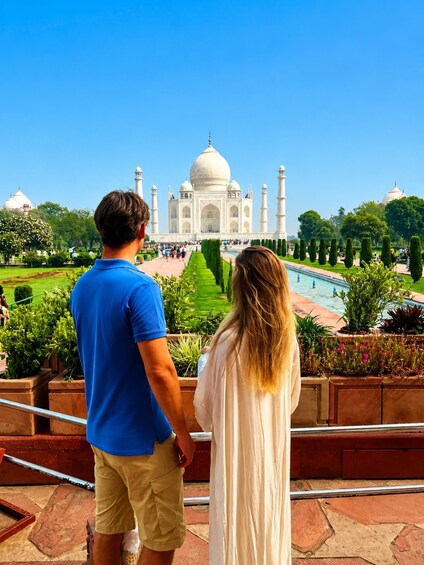 Pariskunta seisoo Taj Mahalin edessä, ja heillä on esteetön näkymä kuuluisan valkoisesta marmorista rakennettuun mausoleumiin ja sen ympärillä oleviin puutarhoihin. 2