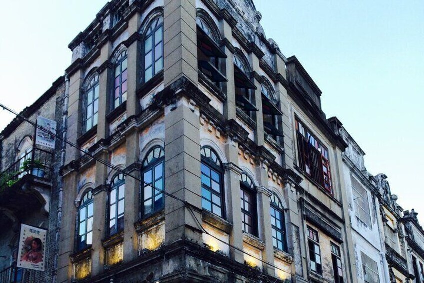 A historic building with ornate architecture, large windows, and a sign on the left. 2