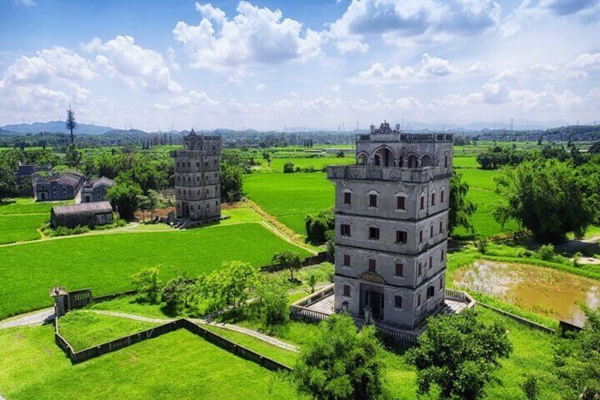 A historical tower complex with multiple structures in a lush green landscape. 1