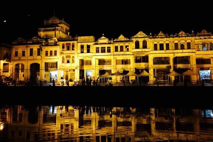 A brightly lit historic building with a reflection in the water. 3
