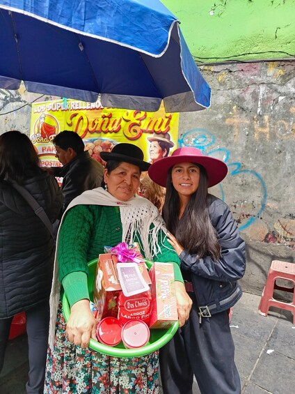 A street vendor with a cart under a blue umbrella, holding a tray with food items and a phone. 4