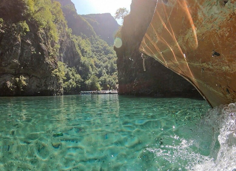 A boat in a clear, turquoise river surrounded by lush green cliffs. 5