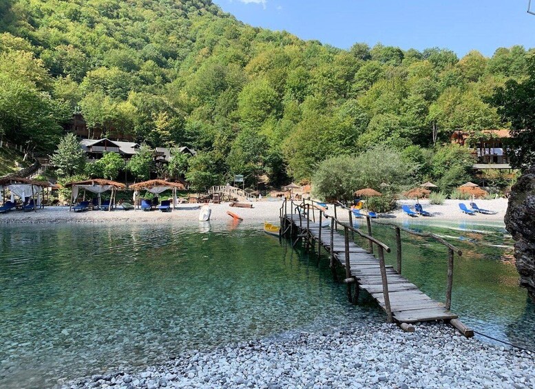 A wooden pier extending into a clear lake surrounded by a forested hillside. 3