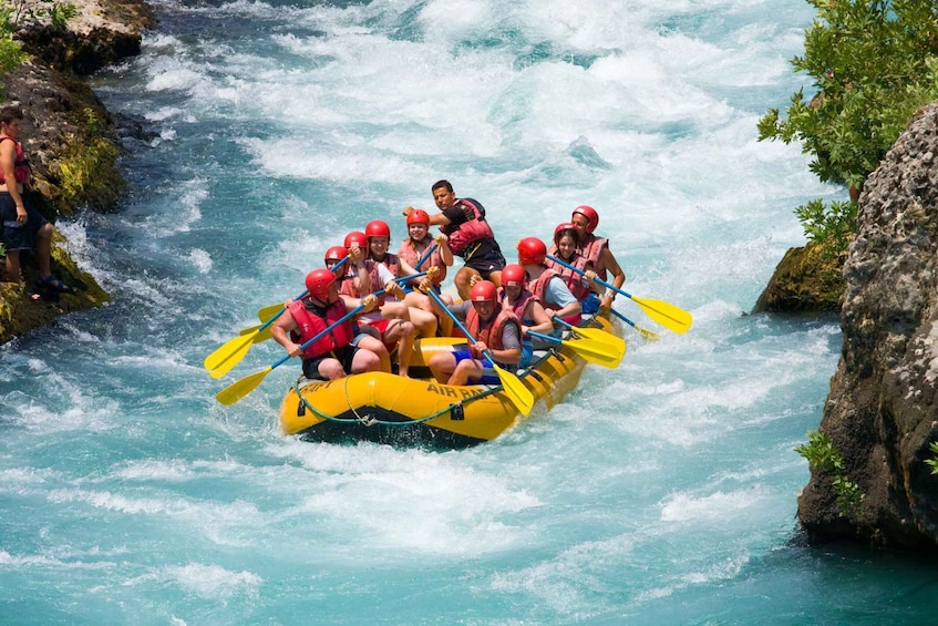 A group of people in a yellow raft navigating a river with rapids. 1