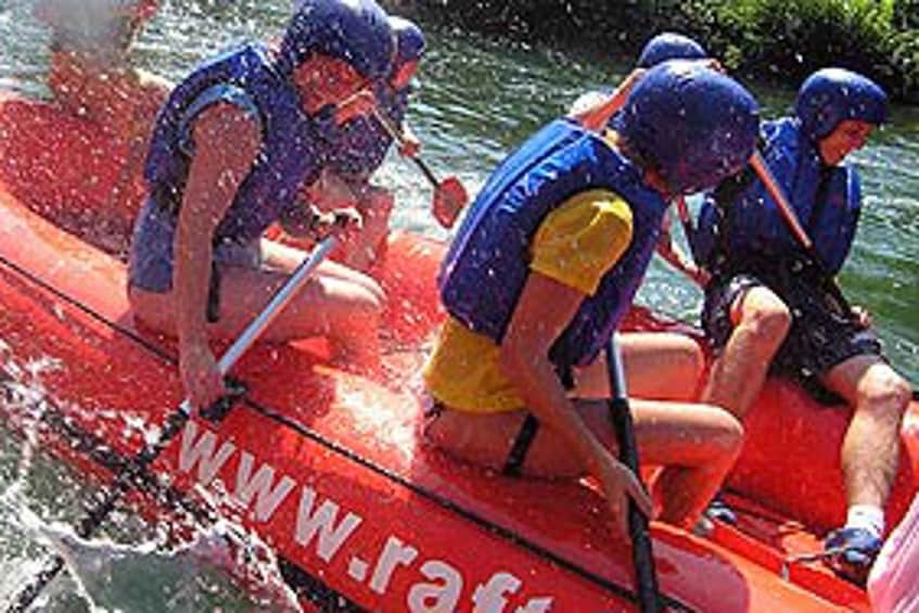 People in a red raft with water splashing around them. 3