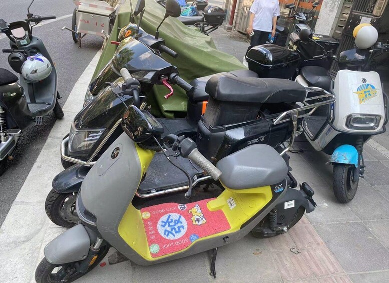 A yellow and gray scooter parked on a street with other scooters. 4