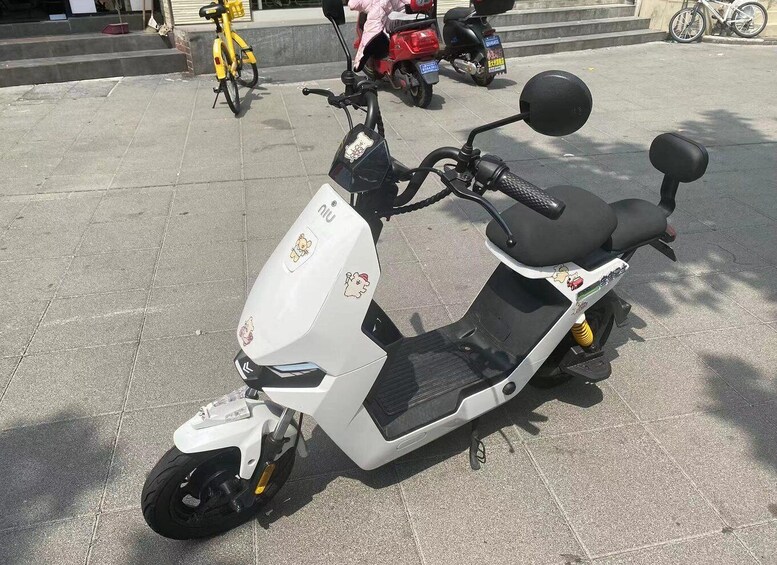 A white electric scooter parked on a tiled surface. 3