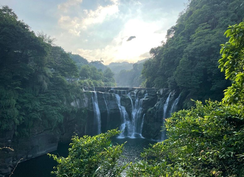 A waterfall cascading down a rocky cliff surrounded by dense greenery. 4