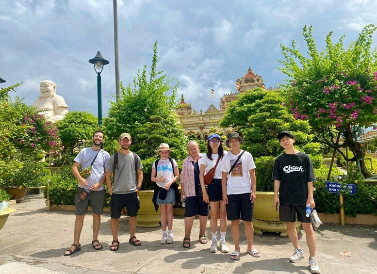 A group of people standing in front of a large statue and a temple with a golden roof. 4
