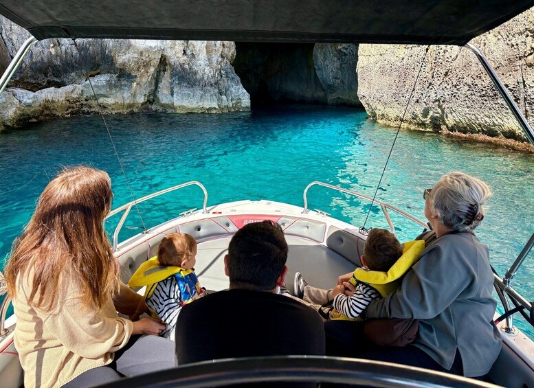 A boat with passengers, clear turquoise water, and rocky cliffs. 5