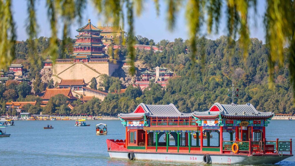 Perinteinen kiinalainen vene, jossa on koristeellinen arkkitehtuuri, lipuu joella. Taustalla näkyy suuri pagodi. 3