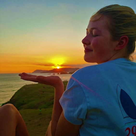 A person sitting by the ocean at sunset. 4