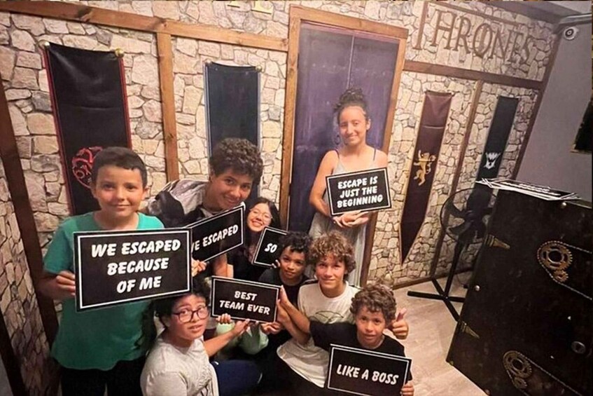 A group of people holding signs in a room decorated with a 'Game of Thrones' theme, including banners and a throne-like chair. 5