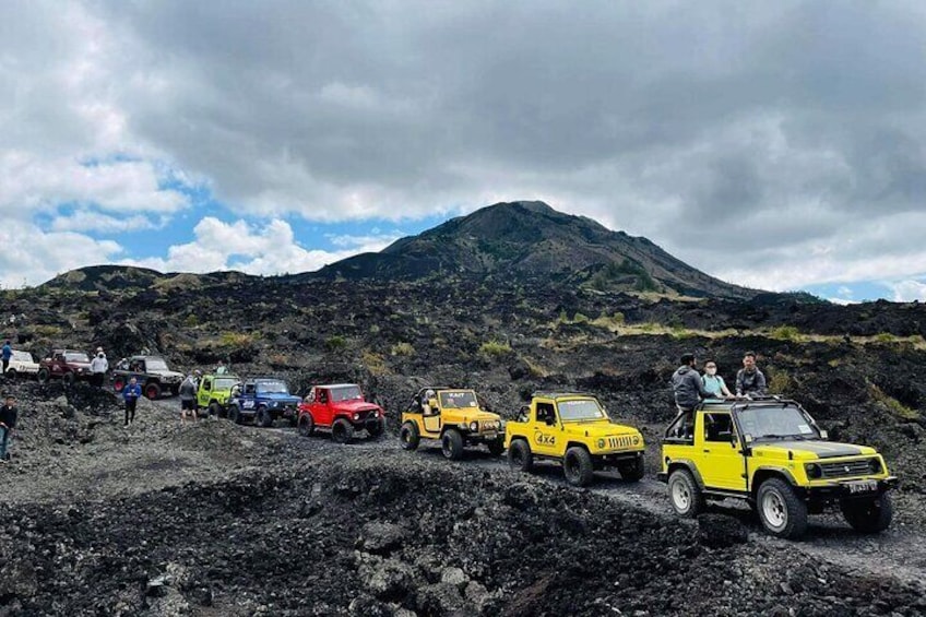 A group of off-road vehicles parked on a rocky terrain with a mountain in the background. 4