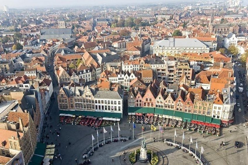 En stadsbild med historiska byggnader, ett centralt torg och en framträdande staty. 2
