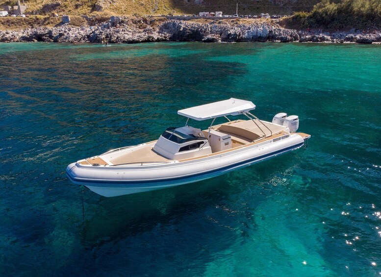 Een witte motorboot met een zonnedak, drijvend in helder turquoise water nabij rotsachtige oevers. 1