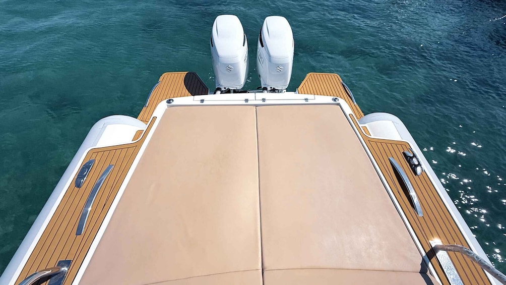 Het dek van een boot met twee buitenboordmotoren, een beige zonnescherm en houten leuningen. 4