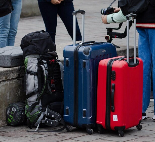 Three suitcases, one blue and one red, with a black backpack and a green bag nearby. 2