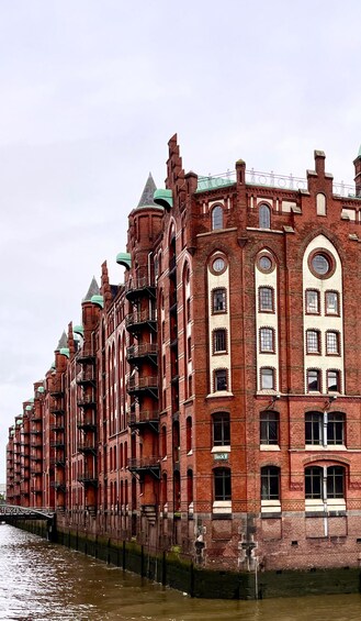 A row of red brick buildings with green roofs and multiple windows. 3