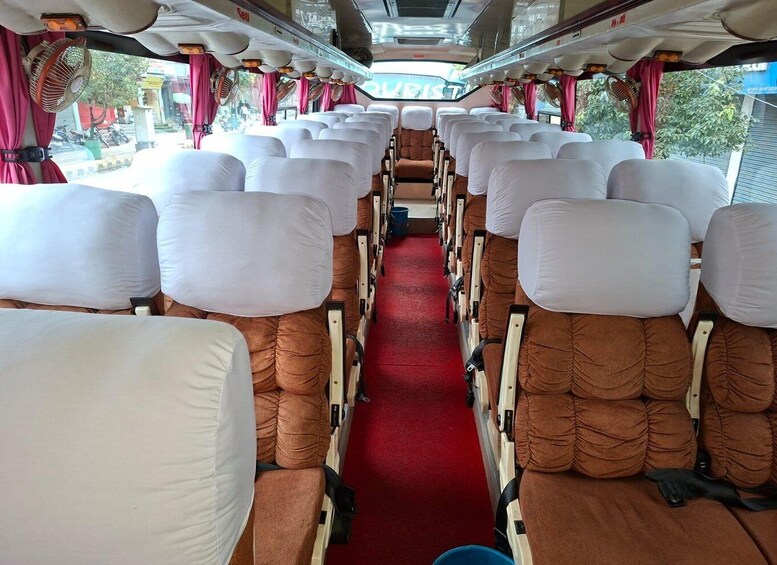 A train interior with rows of seats, red carpeting, and fans. 2