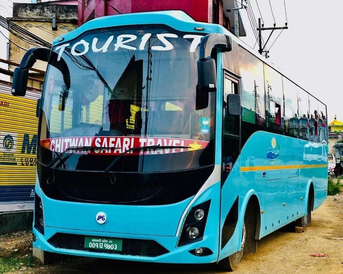 A turquoise bus with 'TOURIST' written on the windshield and 'CHITWAN SAFARI TRAVEL' on the side. 3