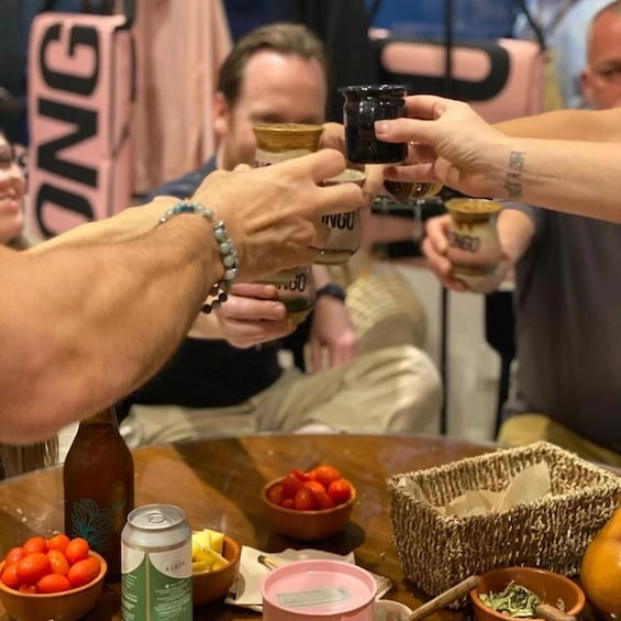 Un gruppo di persone brinda con bevande, un tavolo imbandito di cibo e bevande, e un cesto di vimini. 1