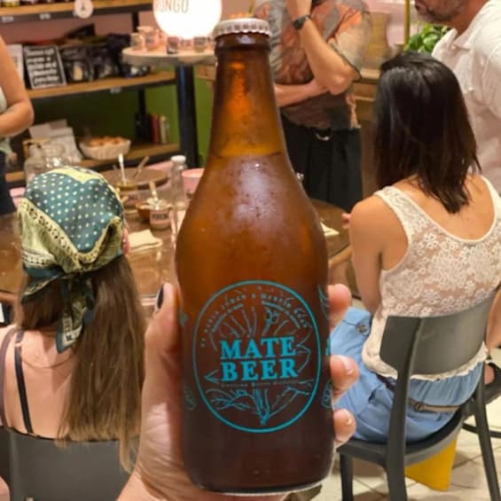Una persona che tiene una bottiglia di birra Mate con etichetta. 3