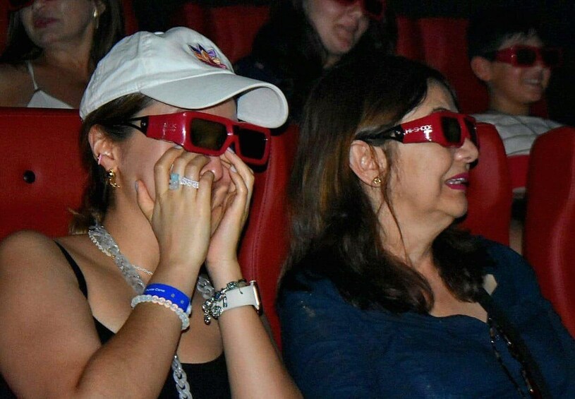 Two people wearing red 3D glasses in a theater. 5