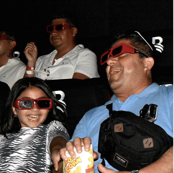People wearing red 3D glasses, holding popcorn, and a black bag with a camera. 3