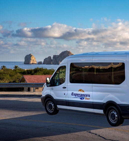 A white van with 'Esperanza's Tours' on the side parked on a road with a coastal landscape in the background. 4