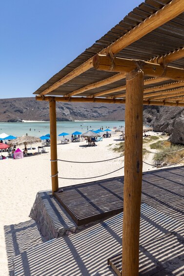 A beach with wooden structures, umbrellas, and people. 2
