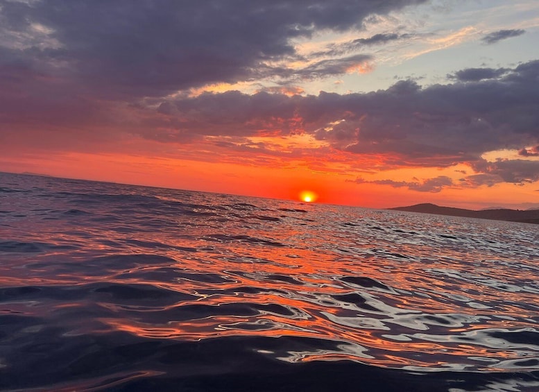 A sunset over a body of water with waves reflecting the colors of the sky. 3