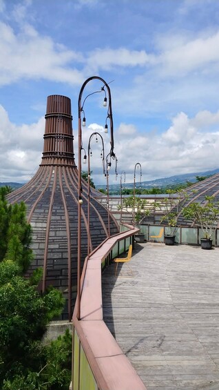 A rooftop terrace with a unique conical roof structure, metal railings, and potted plants. 3