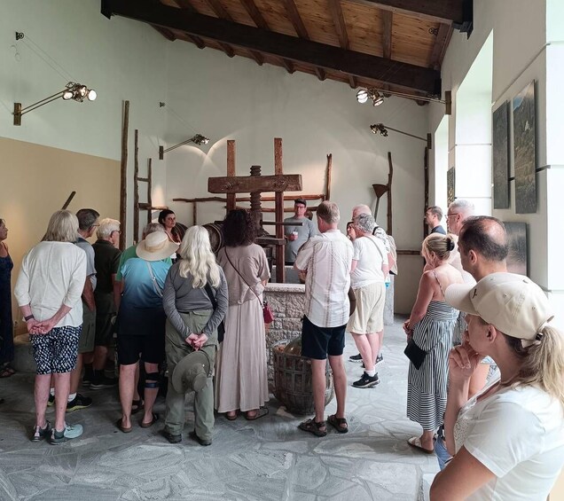 A group of people gathered around a wooden structure in a building with stone flooring and wooden beams on the ceiling. 1