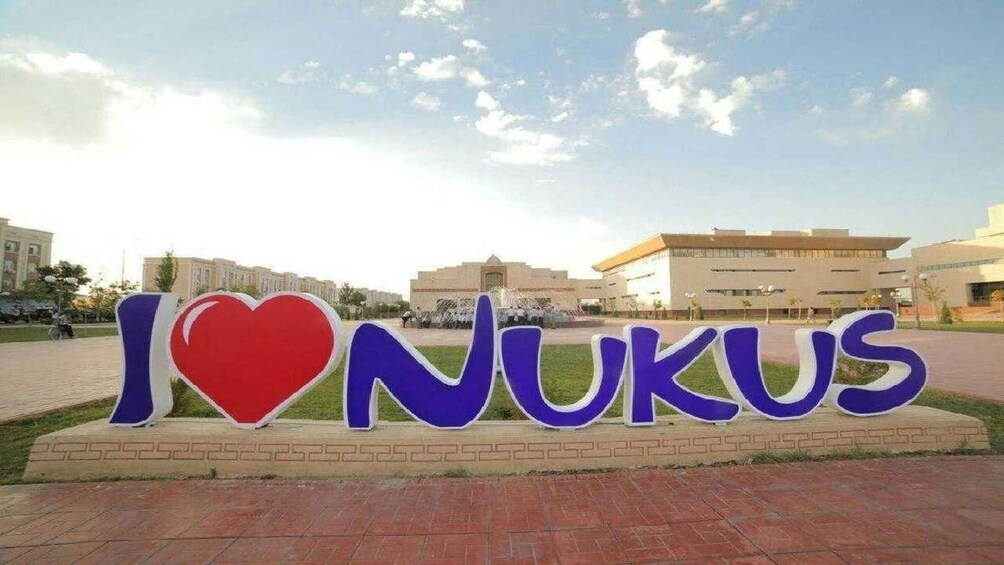 A sign with 'I ♥ NUKUS' in front of a building. 1