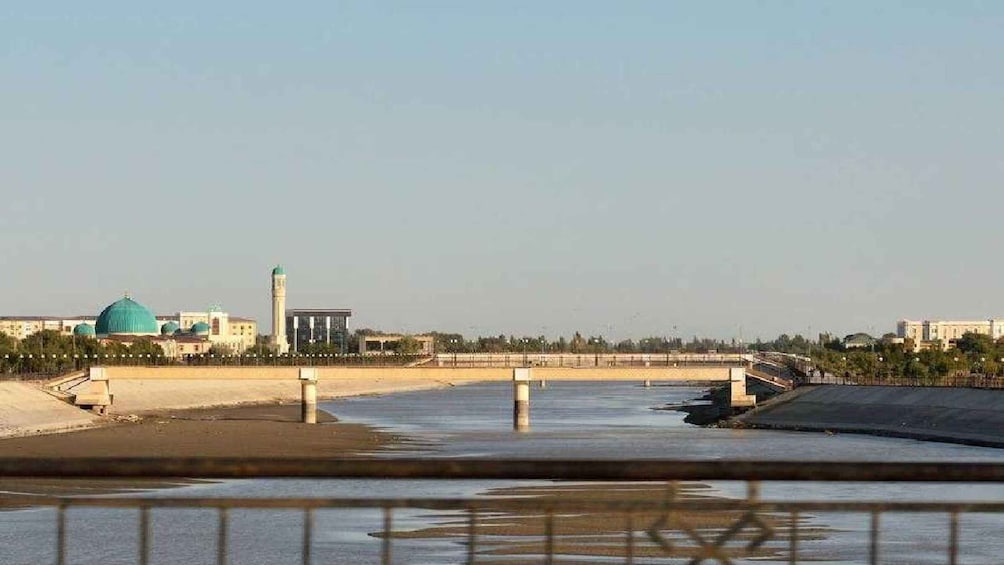 A river with a bridge, a mosque with a green dome, and a minaret. 3