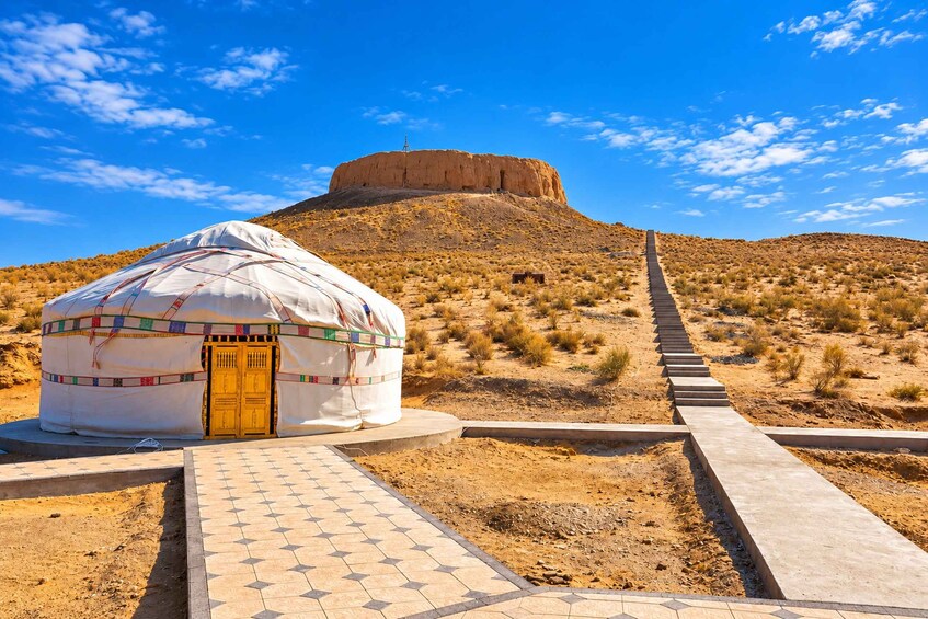 A yurt with a paved walkway leading to a mountain. 1
