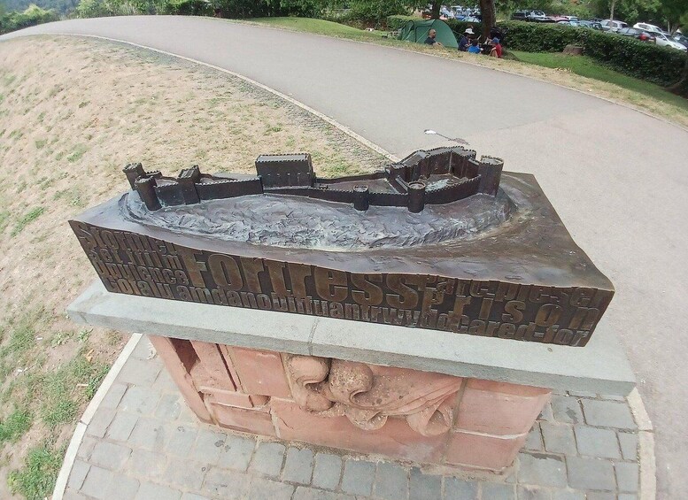A bronze monument with inscriptions and a relief sculpture of a fort. 4